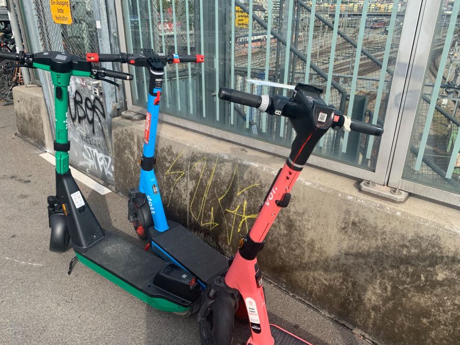 Bei den Trottis von Dott (Mitte) ist der Hinweis zwar oben an der Lenkstange angebracht, kann auf dem schwarzen Grund aber leicht übersehen werden.