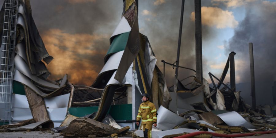 dpatopbilder - Ein ukrainischer Feuerwehrmann vor einem zerstörten Lagerhaus. Foto: Francisco Seco/AP/dpa/Archivbild