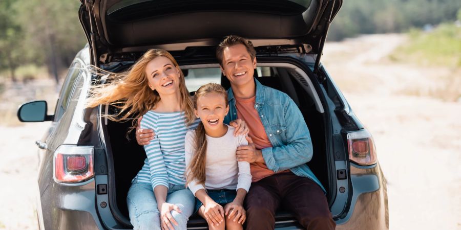 Familie im Kofferraum des Autos lachend