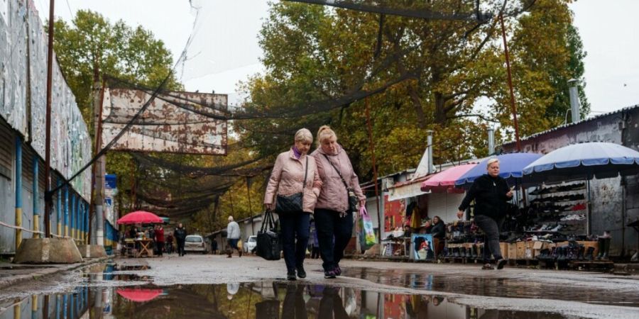 Frauen gehen während einer lokalen Waffenruhe im Zusammenhang mit einer humanitären Hilfsmission in Oleschky in der ukrainischen Region Cherson auf einer mit Anti-Drohnen-Netzen über...