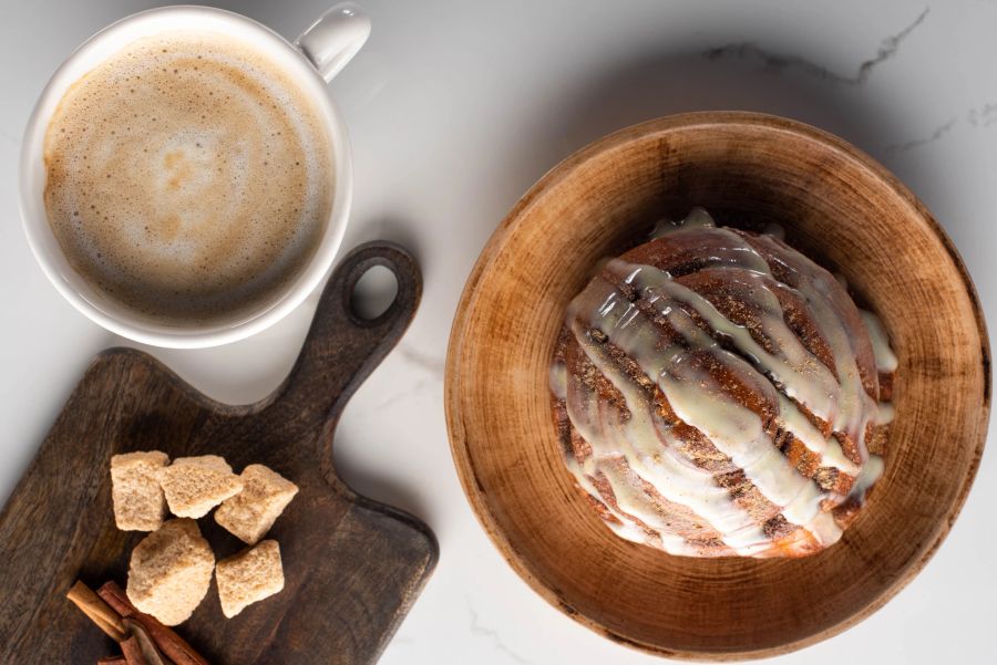 Zuckerhaltige Zimtrolle und Kaffee mit braunem Zucker