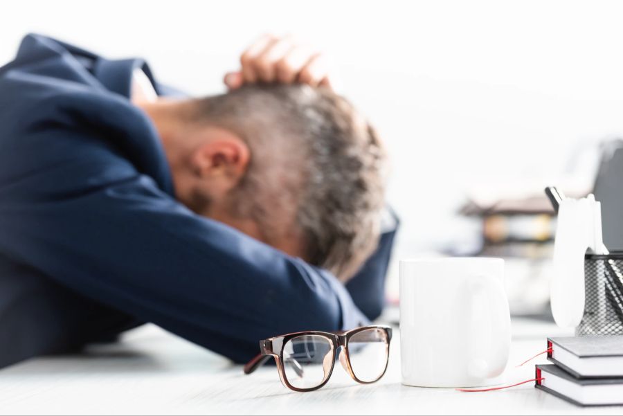 Erschöpfter Mann legt Kopf auf Tisch, Arbeitsbelastung