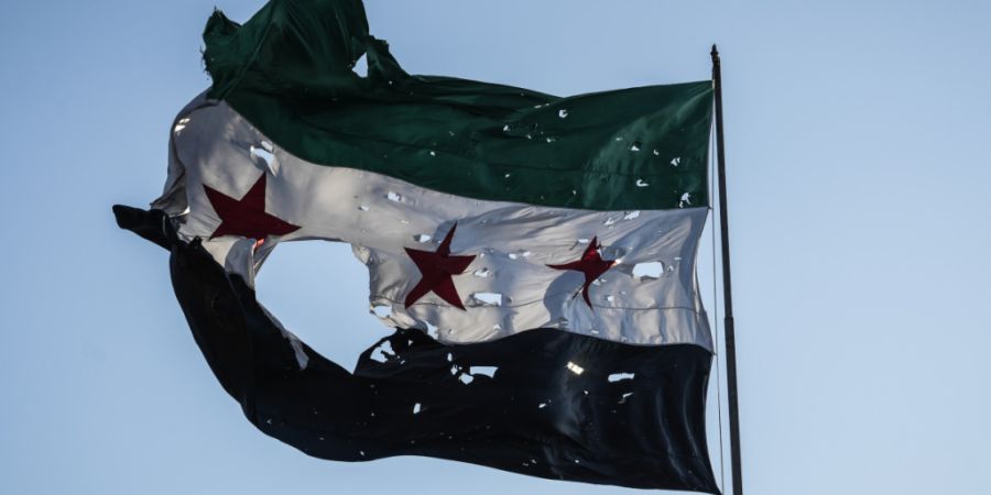 ARCHIV - Eine zerfetzte syrische Flagge weht vor dem syrischen Generalstabshauptquartier. Foto: Moawia Atrash/dpa/Symbolbild