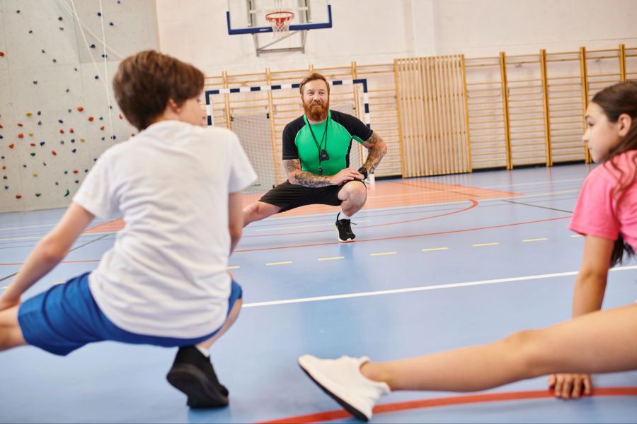 Jugendliche beim Training mit ihrem Trainer in einer Sporthalle