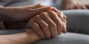 Hände einer jungen Person halten Hand einer älteren Person