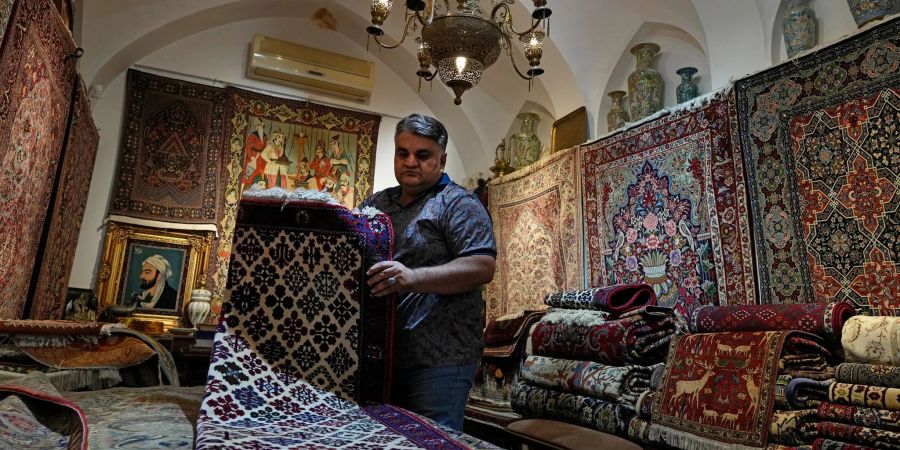 Ein iranischer Teppichhändler arbeitet in seinem Geschäft auf dem traditionellen Basar der Stadt Kashan.