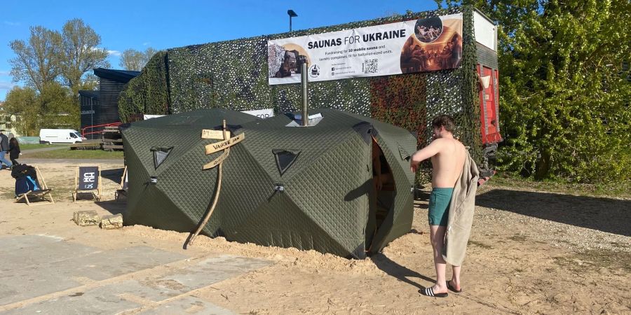 Ein Festival-Besucher steht vor einer mobilen Front-Sauna, die in Estland für die ukrainische Armee entwickelt worden ist.