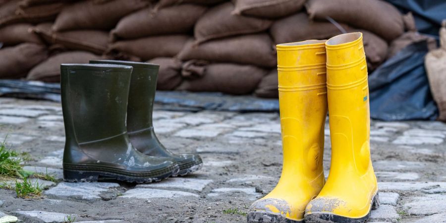 Gummistiefel stehen in der Altstadt vor Sandsäcken. Der Hochwassernachrichtendienst geht von einem baldigen Ende der Hochwasserlage in Bayern aus.