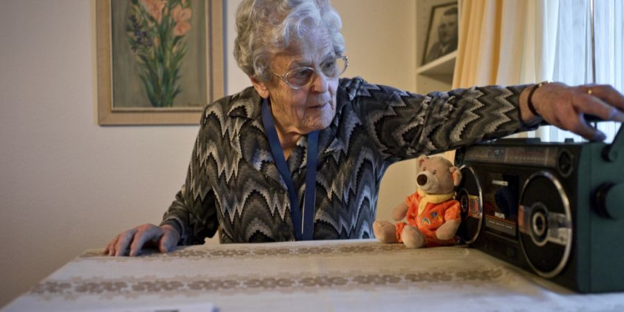 Wie soll künftig in Notfällen kommuniziert werden? Im Bild hört eine ältere Frau im Wohnzimmer ihrer Wohnung Radio.