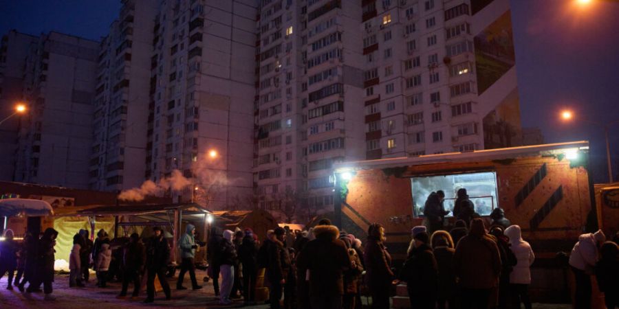 Menschen stehen in Kiew in einer Schlange für kostenlose warme Mahlzeiten an. Russische Luftangriffe auf den Energiesektor des Landes lassen die Menschen im härtesten Winter seit Jahr...