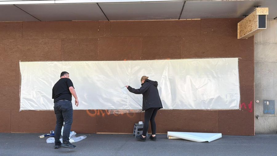 Kaum wurde die Holzwand versprayt, deckten Läderach-Mitarbeitende die Botschaft der Demonstranten mit einer Plastikplane ab.