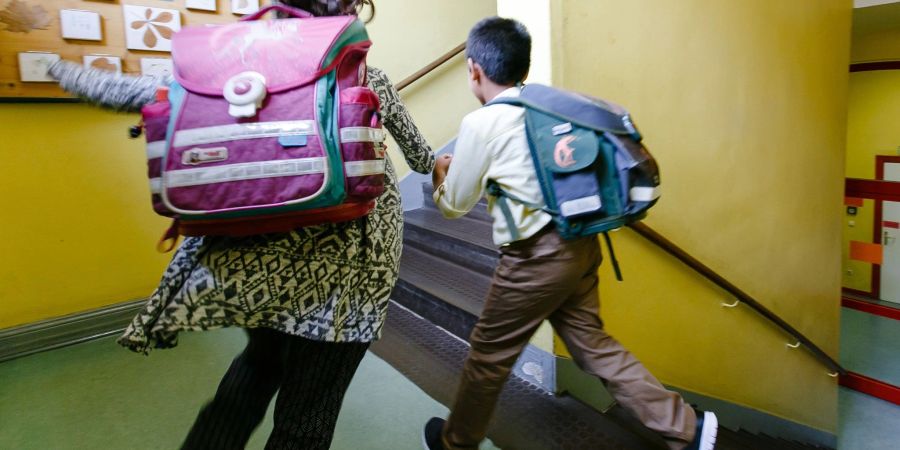 Zwei Kinder laufen durch das Treppenhaus ihrer Grundschule.