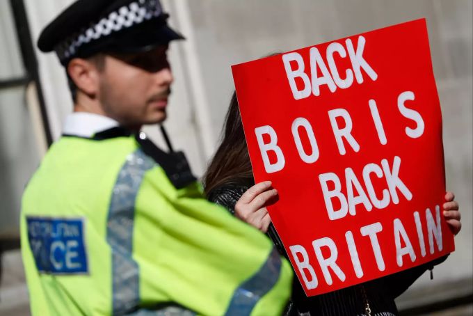 Ein Polizist steht neben einem Pro-Brexit-Demonstranten mit einem Plakat vor dem Supreme Court. Brexit