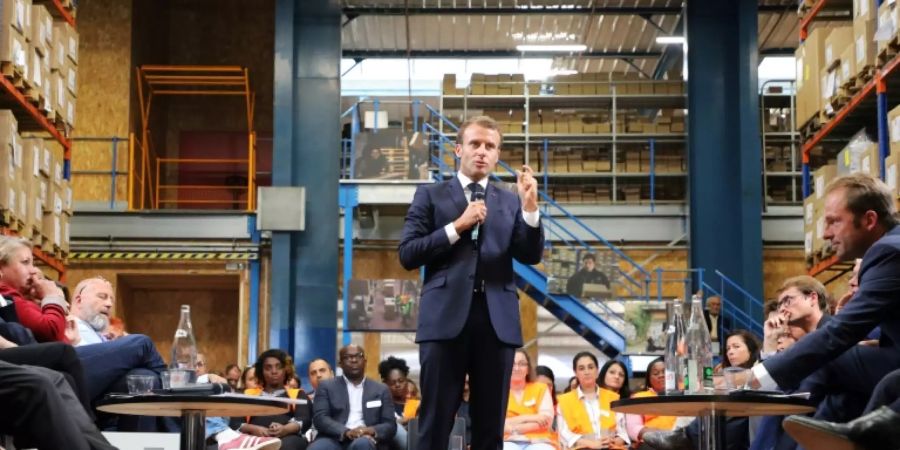 Macron spricht in einer Lagerhalle zu Arbeitern