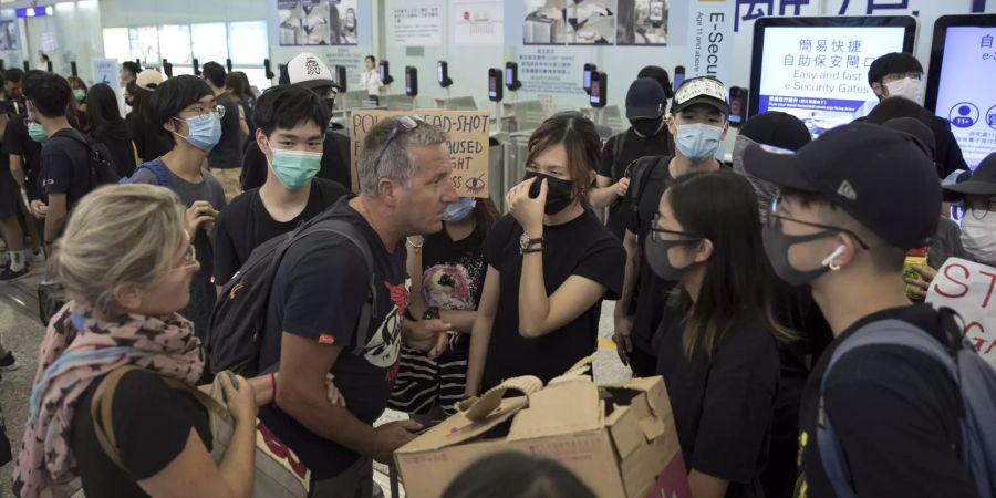 Reisende auf dem Flughafen von Hongkong werden von Demonstrierenden blockiert.