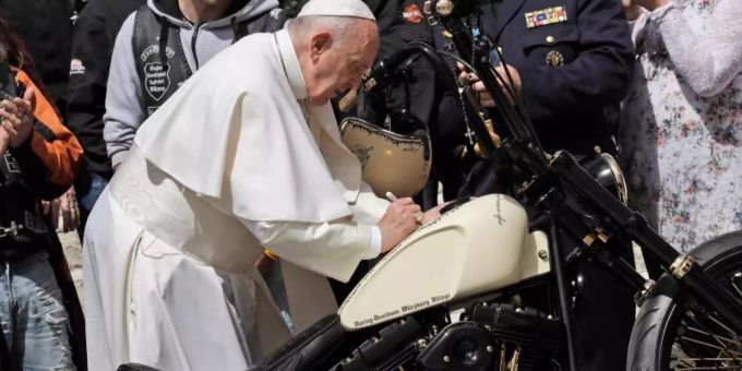 Papst Franziskus unterschreibt auf einer Harley-Davidson, während er Mitglieder der Gruppe «Jesus Bikers International» auf dem Petersplatz trifft. Foto: Alessandra Tarantino Papst Franziskus unterschreibt auf einer Harley-Davidson, während er Mitglieder der Gruppe «Jesus Bikers International» auf dem Petersplatz trifft. Foto: Alessandra Tarantino