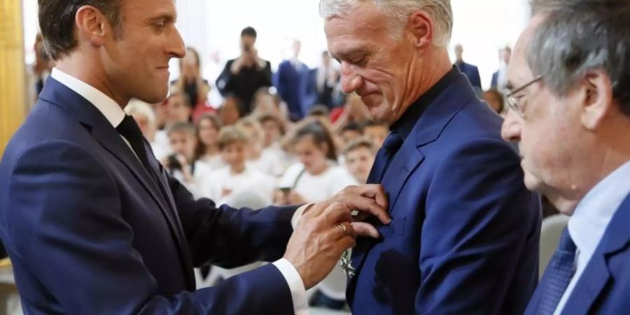 Frankreichs Präsident Emmanuel Macron (l) verleiht die Medaille der Ehrenlegion an Trainer Didier Deschamps. Foto: Francois Mori/AP