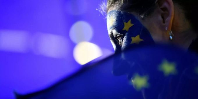 Frau hält vor dem Europaparlament eine EU-Flagge Frau hält vor dem Europaparlament eine EU-Flagge