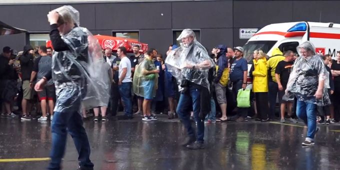 Besucher eines Rammstein-Konzertes stehen vor dem Rudolf-Harbig-Stadion und schützen sich vor dem Regen. Unwetter