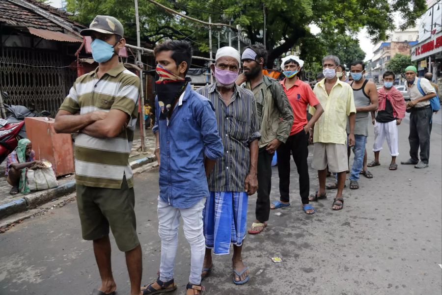 Leute stehen in Kolkata, Indien, an, um Gratis-Nahrung zu erhalten.