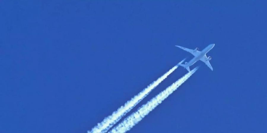 Am blauen Himmel fliegt ein Flugzeug und hinterlässt Kondensstreifen. Foto: Patrick Pleul/dpa-Zentralbild/dpa