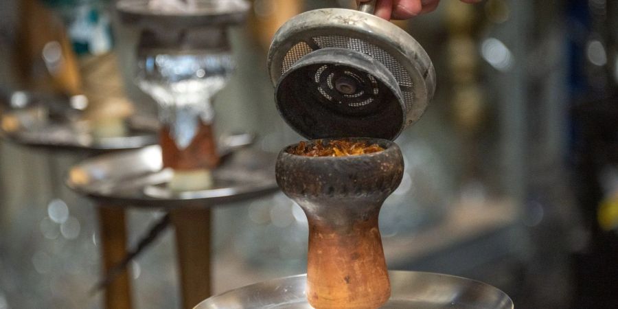 Ein Mitarbeiter füllt in einer Shisha-Bar Tabak in den Kopf der Pfeife.