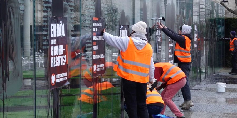 Klimaaktivisten der Letzten Generation beschmieren und plakatieren die gläserne Grundgesetz-Skulptur am Bundestag.