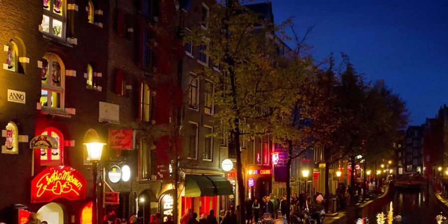 ARCHIV - Menschen schlendern am Abend an einer Gracht entlang durch den Rotlichtbezirk De Wallen. Nach der Lockerung der Corona-Massnahmen kommen die ersten Besucher wieder in die Stadt - doch viele Bewohner wollen den Massen-Tourismus nicht mehr. (zu dpa «Amsterdamer wollen keinen Massen-Tourismus mehr») Foto: Koen Van Weel/epa/dpa