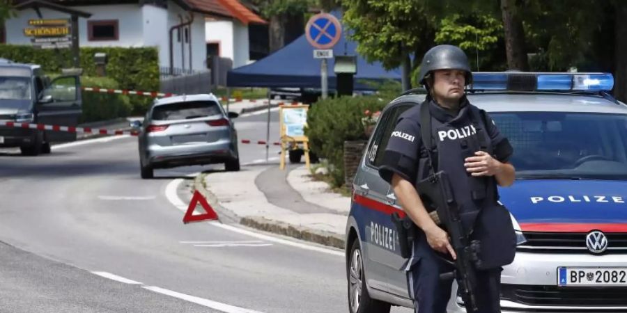 Ein bewaffneter Polizist sichert einen Strassenabschnitt am Tatort einer Tötung in der Gemeinde Villach. Foto: Gert Eggenberger/APA/dpa