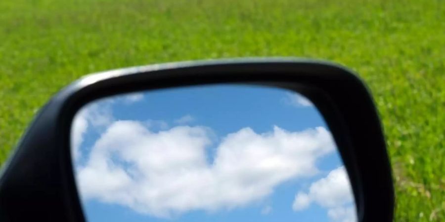 Blauer Himmel und Wolken im Aussenspiegel eines Autos. Foto: Sebastian Willnow/dpa-Zentralbild/dpa