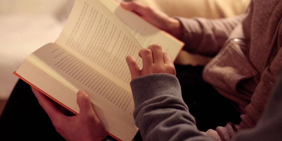 Eine Mutter liest ihrer kleinen Tochter aus einem Buch vor.