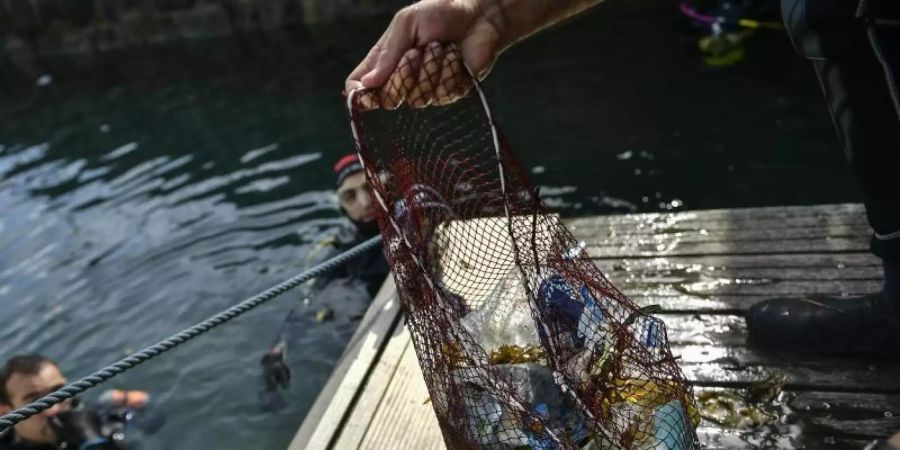 Ein Taucher hält ein Netz mit Abfällen, die er im baskischen Dorf Bermeo aus dem Meer entzogen hat. (Archivbild). Foto: Alvaro Barrientos/AP/dpa