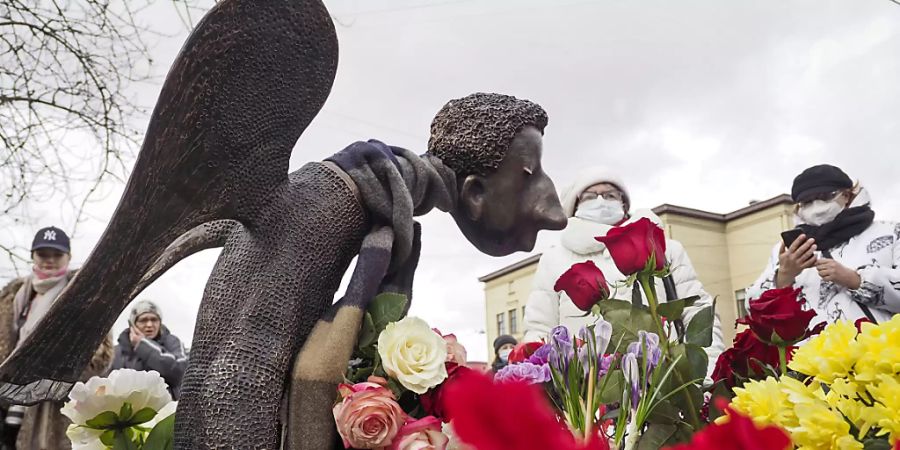 ARCHIV - Menschen stehen vor der mit Blumen umringten Skulptur «Trauriger Engel» des Bildhauers Shustrov, während der Eröffnung einer Gedenkstätte für medizinische Mitarbeiter, die in St. Petersburg an einer Corona-Infektion gestorben sind (Archivbild). Foto: Dmitri Lovetsky/AP/dpa