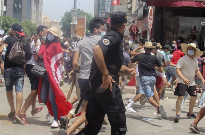 Ein tunesischer Polizist ringt mit Demonstranten während einer Demonstration in Tunis, Tunesien, Sonntag, 25. Juli 2021. Tunesien