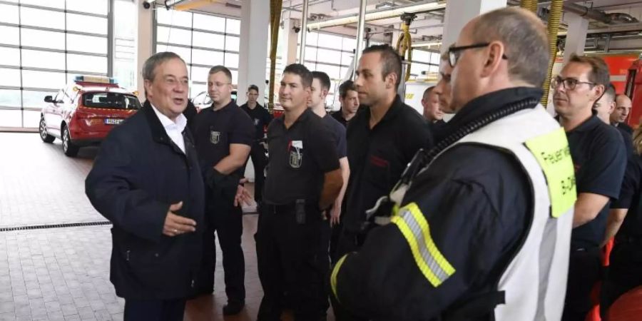 Der nordrhein-westfälische Ministerpräsident Armin Laschet (CDU, l) bedankt sich bei Hagenern Feuerwehrleuten für ihren Einsatz. Foto: Roberto Pfeil/dpa