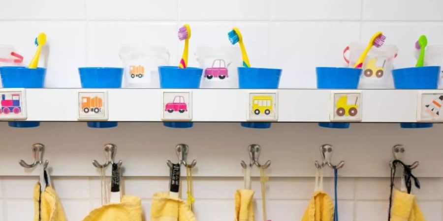 Handtücher und Zahnputzbecher hängen und stehen in einer Kindertagesstätte im Waschraum. Foto: Sebastian Kahnert/dpa-Zentralbild/dpa