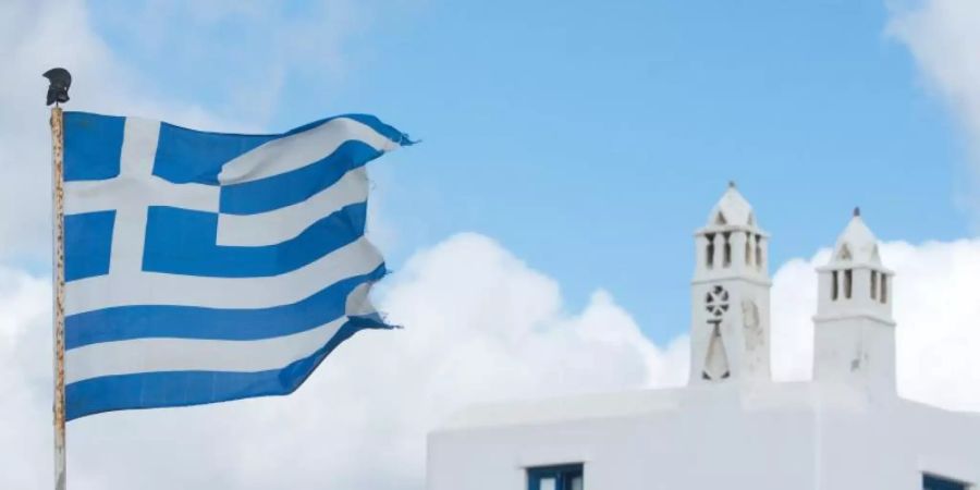 Die griechische Fahne weht auf der Insel Mykonos. Foto: Andrea Warnecke/dpa-tmn/dpa