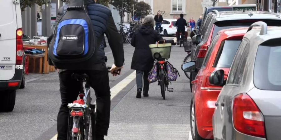 In Karlsruhe fahren Fahrradfahrer an Autos vorbei, die auf einem Parkstreifen stehen. Foto: Uli Deck/Illustration