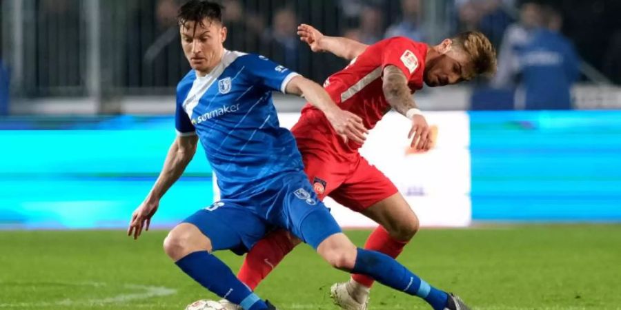 Magdeburgs Charles-Elie Laprevotte (l) und Niklas Dorsch vom FC Heidenheim kämpfen um den Ball. Foto: Peter Steffen/dpa