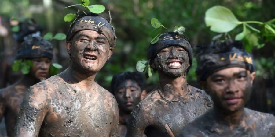 Hindus auf Bali reiben sich rituell mit Schlamm ein