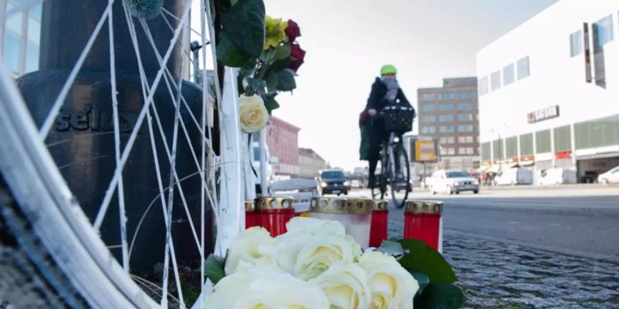 Blumen und Kerzen sind vor einem weissen Geisterrad an der Stelle eines tödlichen Radunfalls in Berlin-Mitte aufgestellt. Foto: Paul Zinken