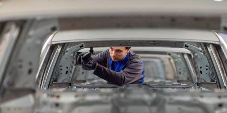 Ein Mitarbeiter schraubt im Karosseriebau im Werk in Wolfsburg an einem Volkswagen. Foto: Christophe Gateau