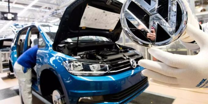Ein Mitarbeiter zeigt ein Logo kurz vor Einbau in einen VW Touran in der Endmontage im VW Werk. mitarbeiter vw