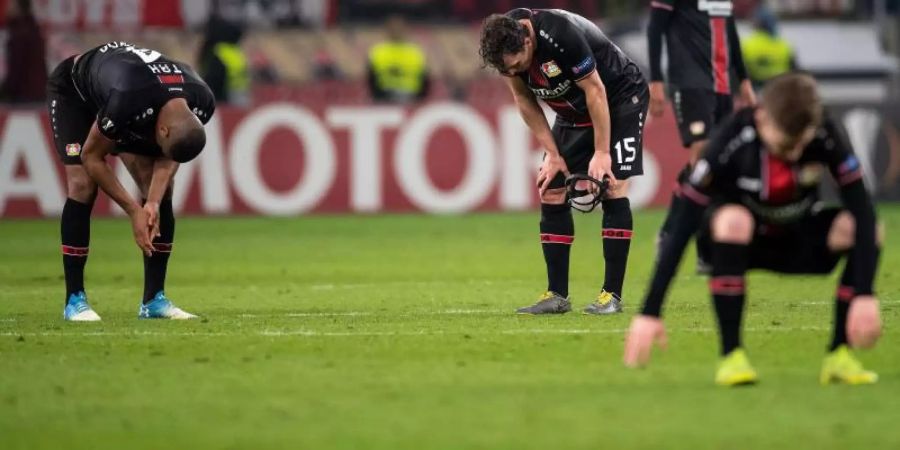 Die Leverkusener Spieler lassen nach dem Ausscheiden die Köpfe hängen. Foto: Marius Becker