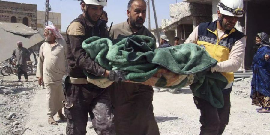 Mitglieder der sogenannten Weisshelme tragen in Idlib ein Opfer eines Luftangriffs auf einen Markt weg. Foto: Syrian Civil Defense White Helmets