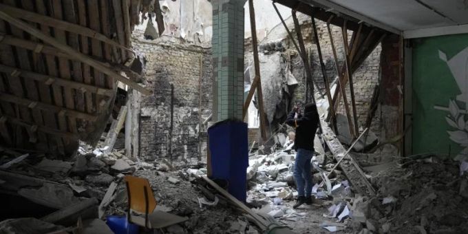 Eine Frau fotografiert ein zerstörtes Unterkunftsgebäude in der Nähe eines Kontrollpunktes in Brovary. Ukraine-Krieg