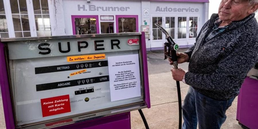 Hans Brunner steht an einer Zapfsäule seiner Tankstelle. Die Tankstelle zeigt Benzin- und Dieselpreise halbliterweise an. Foto: Armin Weigel/dpa