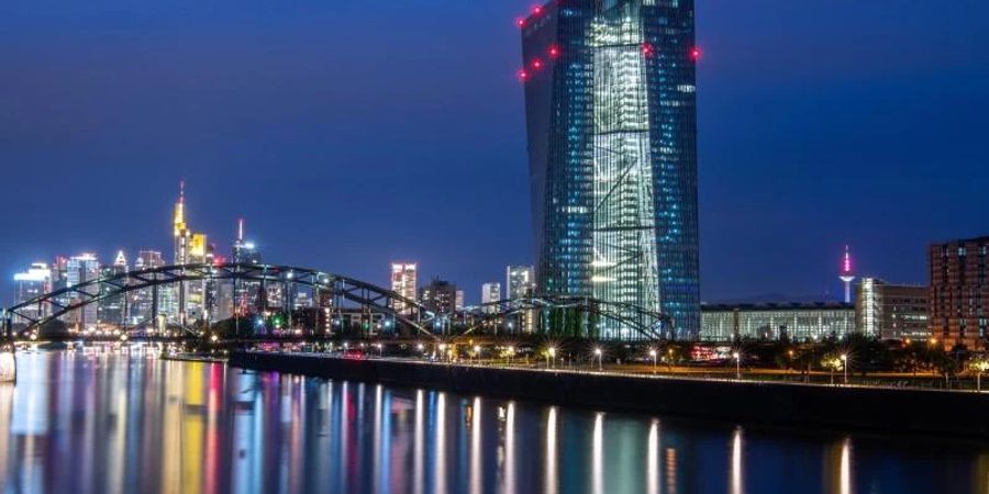 Die Lichter der Europäischen Zentralbank sowie der Frankfurter Bankenskyline spiegeln sich im Main. Foto: Boris Roessler/dpa