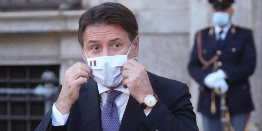 Giuseppe Conte, Ministerpräsident von Italien, richtet seinen Mund-Nasen-Schutz bei einer Pressekonferenz. Foto: Mauro Scrobogna/LaPresse/AP/dpa