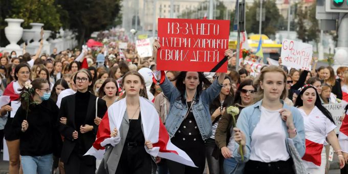 Frauen, von denen einige mit der historischen Flagge von Belarus marschieren. Proteste in Belarus